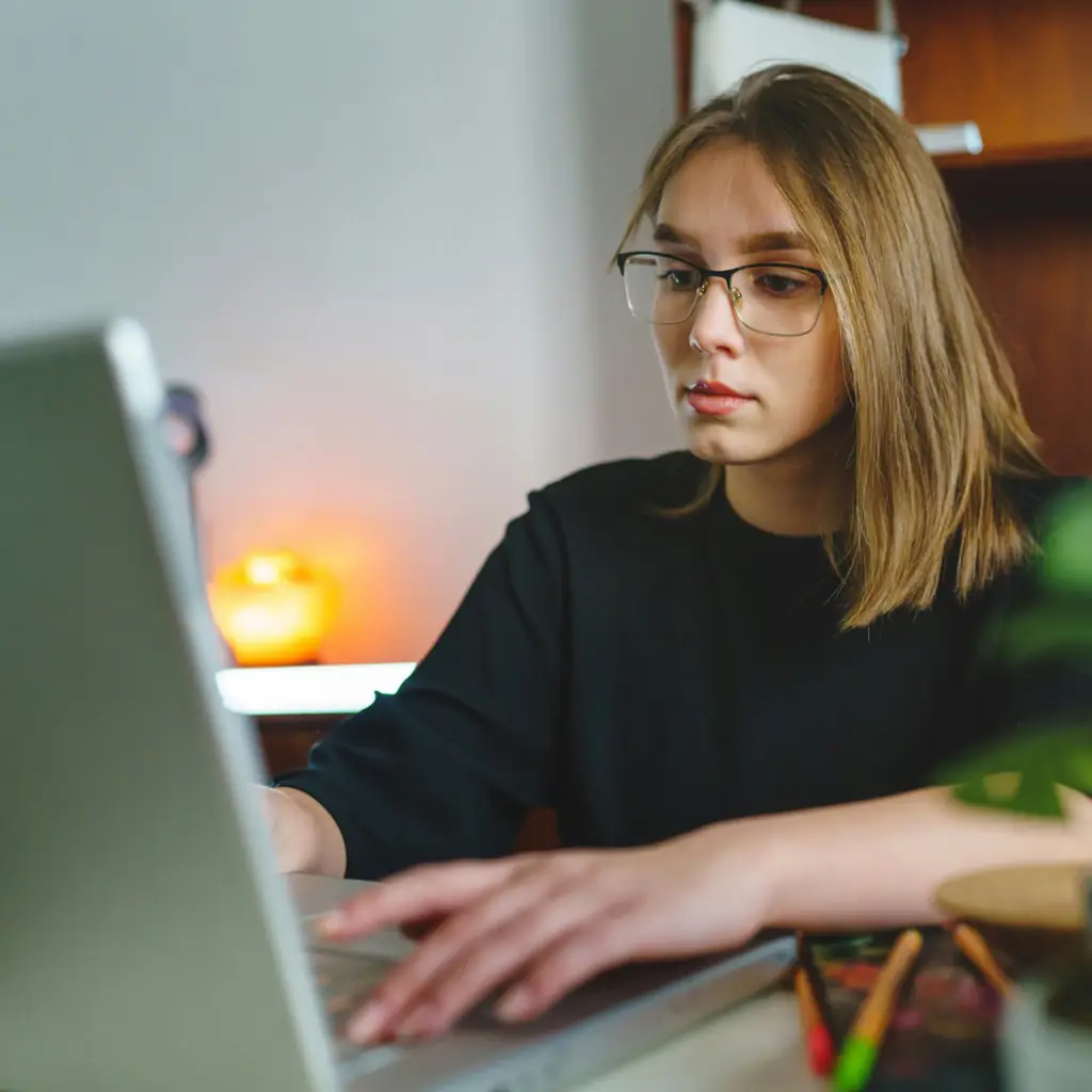 A young woman in glasses working on a computer.